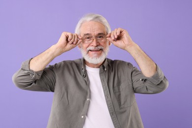 Portrait of stylish grandpa with glasses on purple background