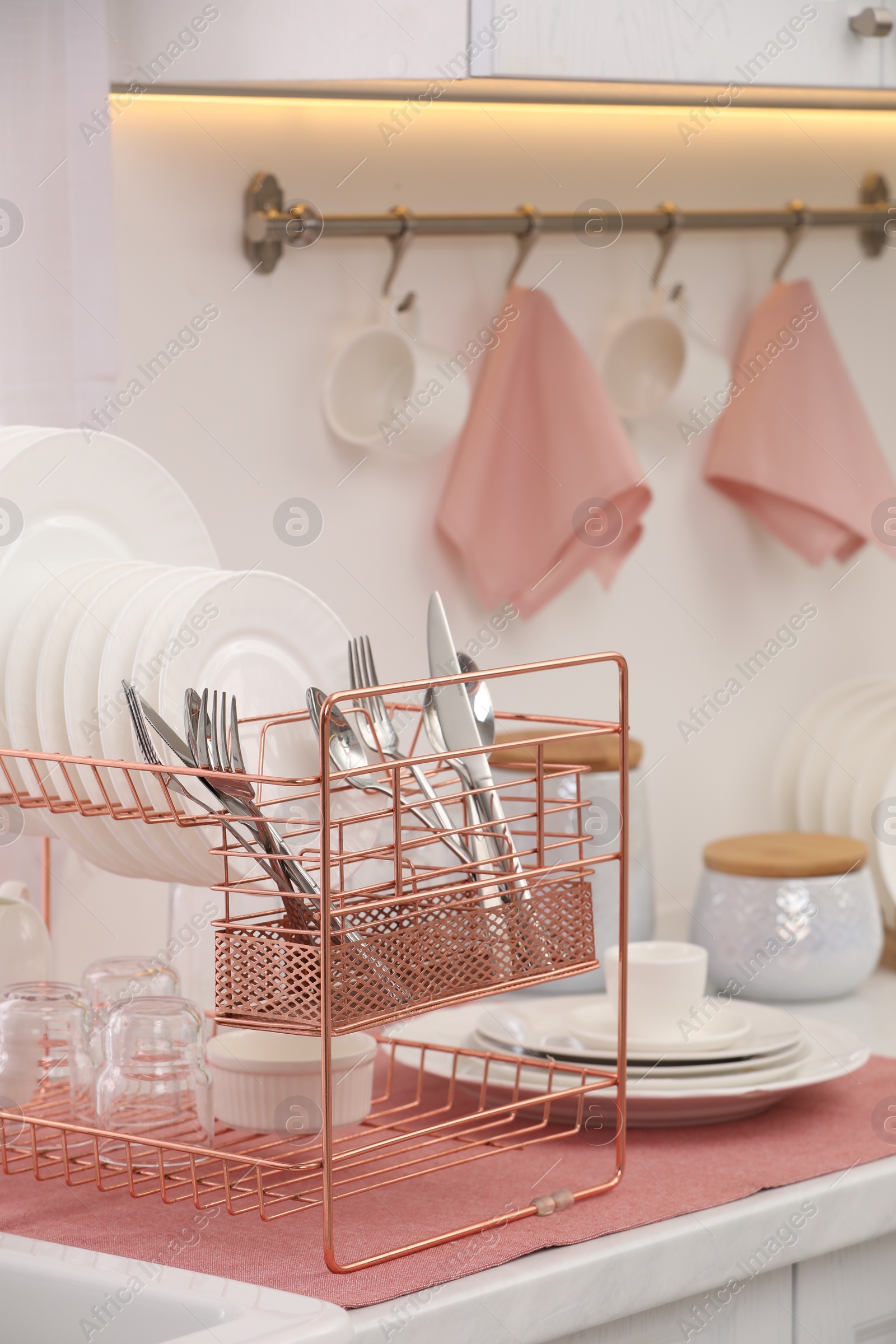 Photo of Drying rack with clean dishes and cutlery on countertop in kitchen