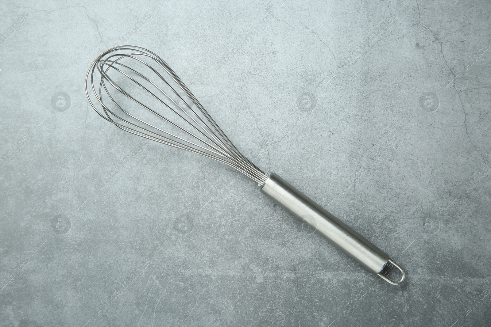 Photo of Metal whisk on gray table, top view