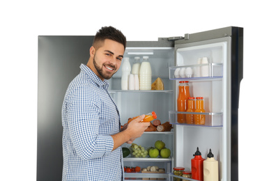 Photo of Young man taking juice out of refrigerator on white background