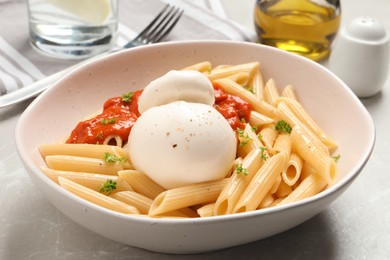 Photo of Delicious pasta with burrata cheese and sauce on light grey table