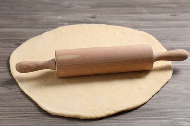 Photo of Raw dough and rolling pin on wooden table