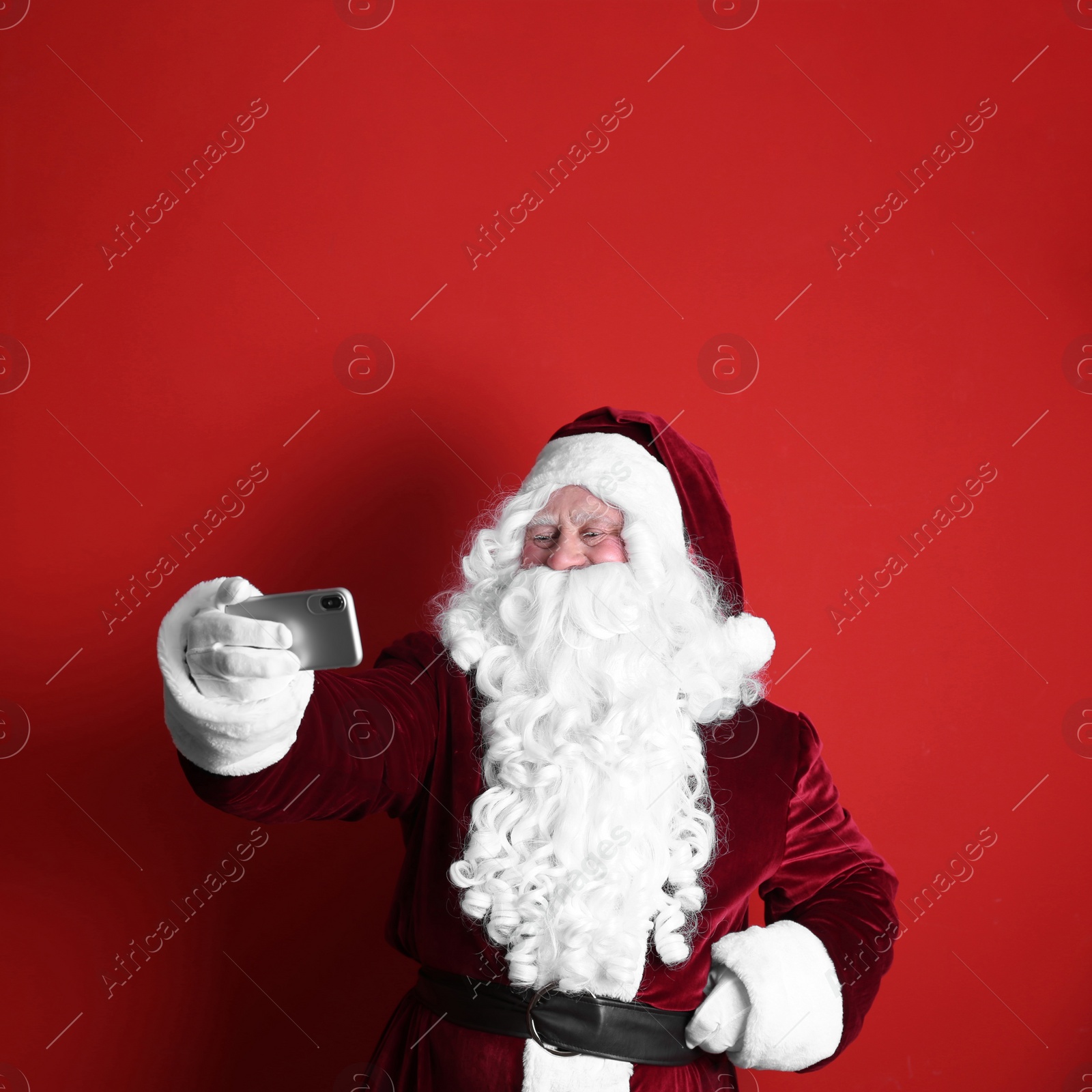 Photo of Authentic Santa Claus taking selfie on red background