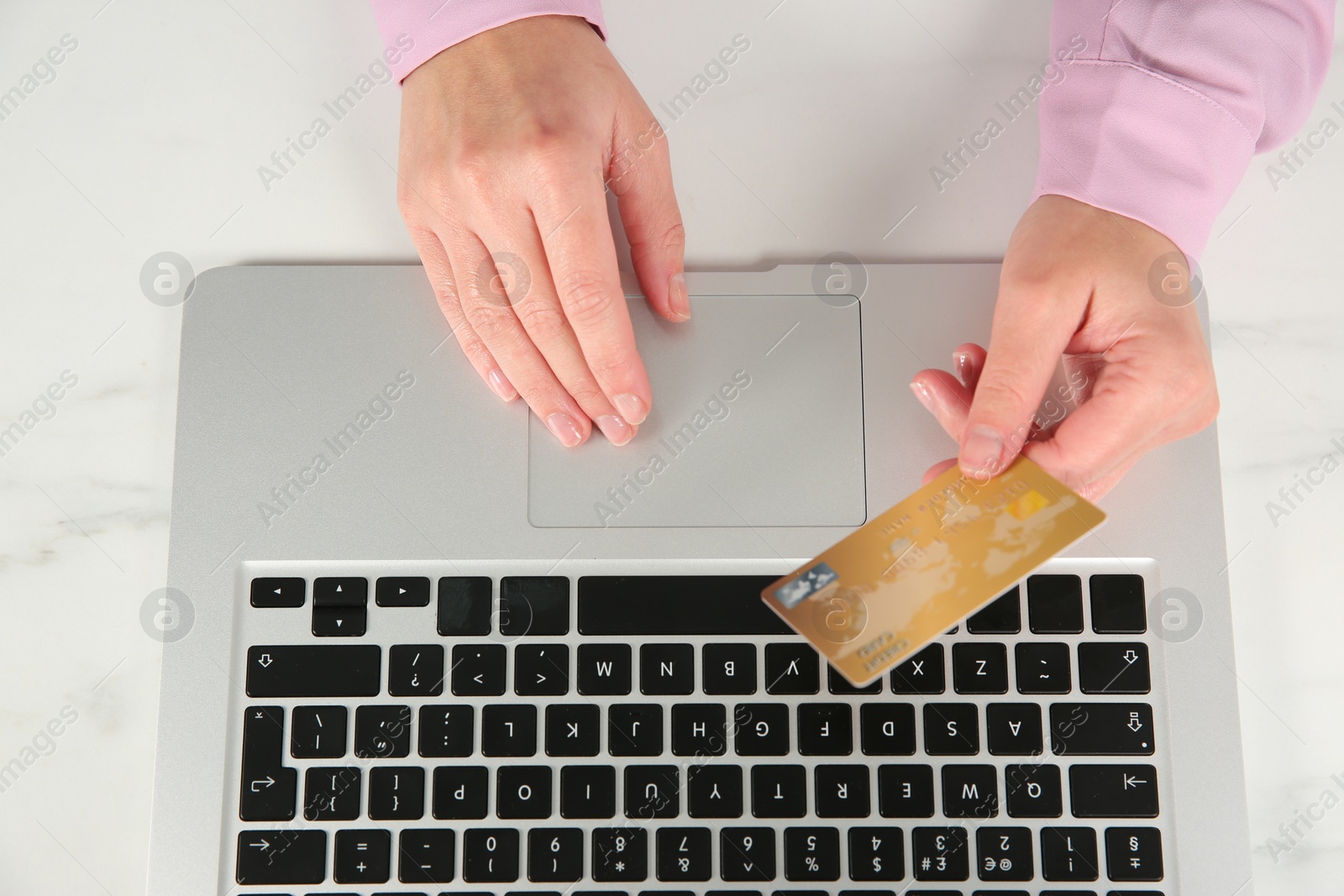 Photo of Online payment. Woman using credit card and laptop at white marble table, top view