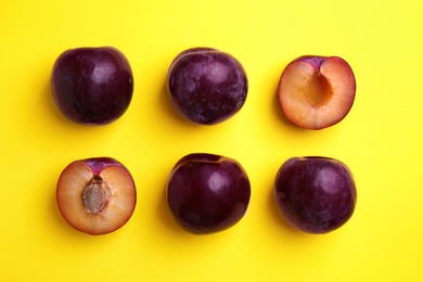 Delicious ripe plums on yellow background, flat lay