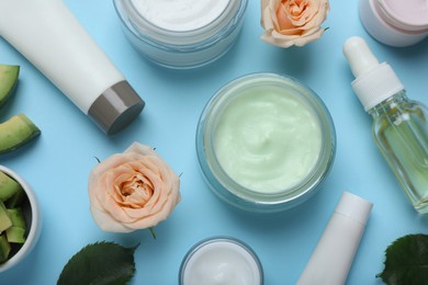Photo of Body cream and other cosmetic products with ingredients on light blue background, flat lay