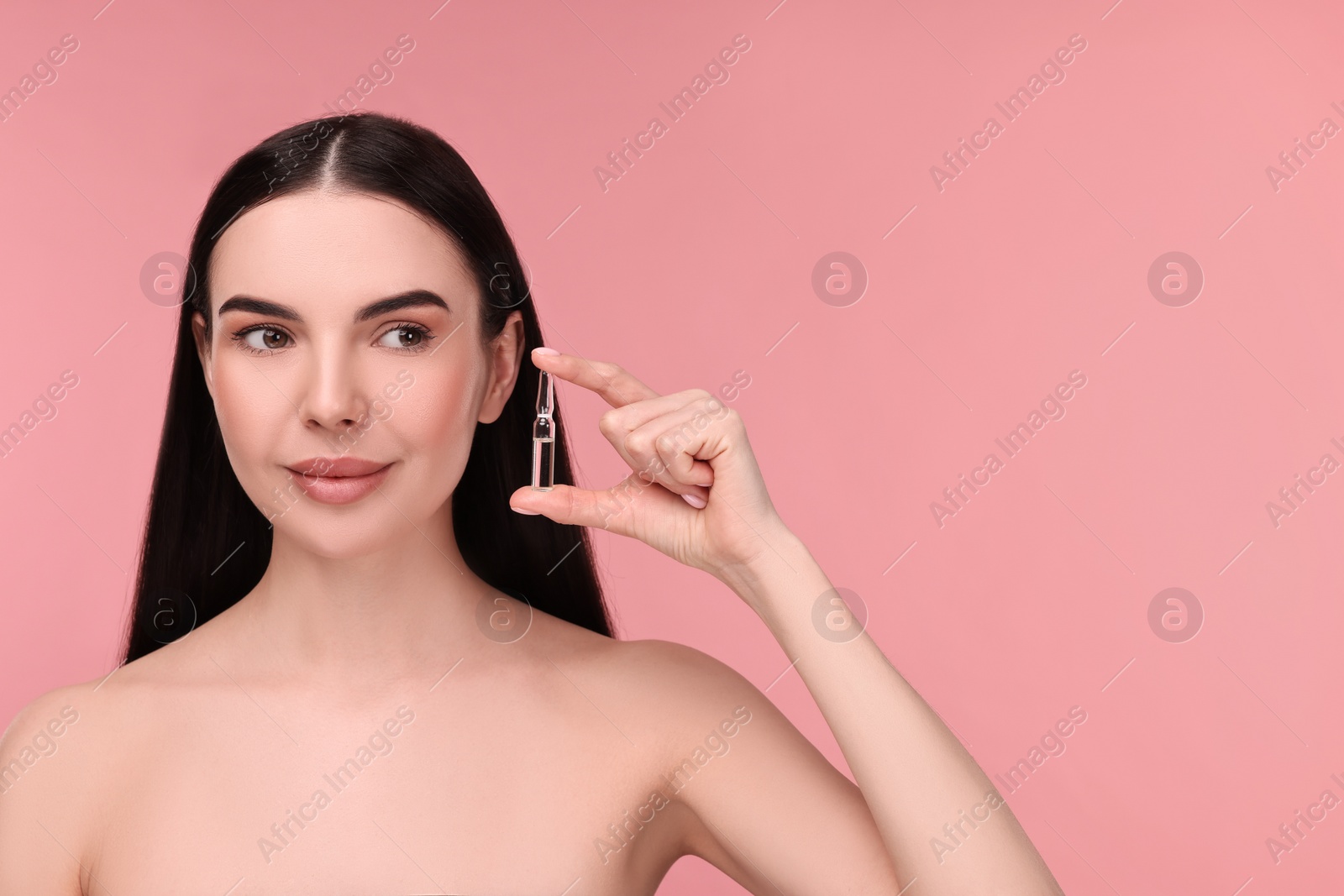 Photo of Beautiful young woman holding skincare ampoule on pink background. Space for text