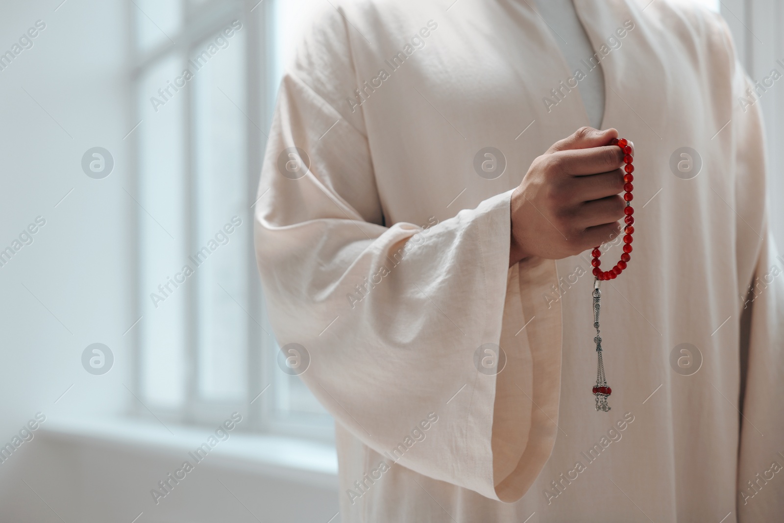 Photo of Muslim man with misbaha indoors, closeup. Space for text