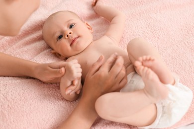 Photo of Woman applying body cream onto baby`s skin on bed, closeup