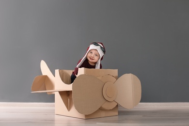 Photo of Adorable little child playing with cardboard plane indoors