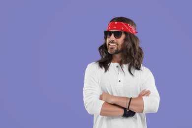 Stylish hippie man in sunglasses on violet background, space for text