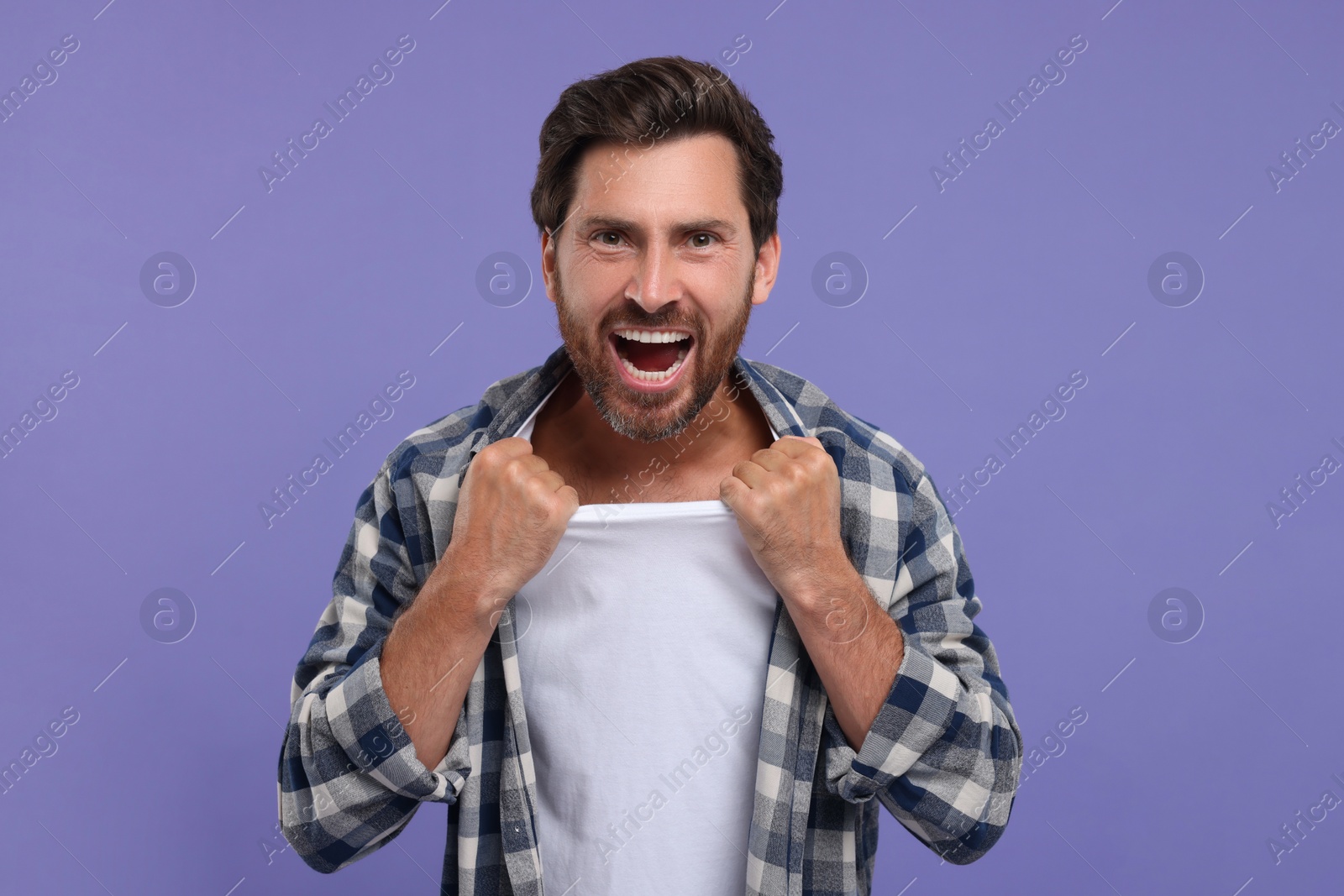 Photo of Emotional sports fan celebrating on purple background