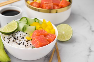 Delicious poke bowl with salmon, lime and vegetables on white marble table, closeup. Space for text