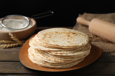 Photo of Many tasty homemade tortillas and rolling pin on wooden table