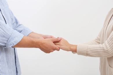 Man holding woman's hands on light background. Concept of support and help