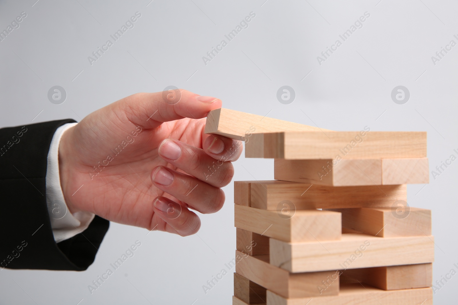 Photo of Woman playing Jenga on light gray background, closeup