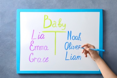 Photo of Woman writing list of baby names on white board, closeup