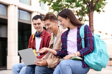 Photo of Happy young students with laptop learning together outdoors