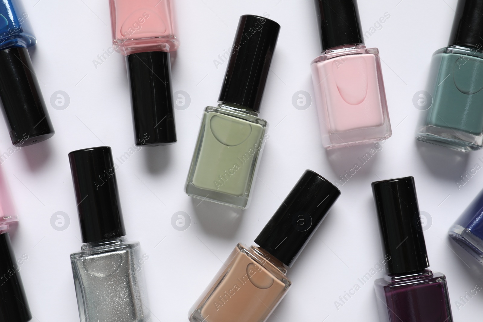 Photo of Nail polishes on white background, flat lay