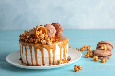 Photo of Delicious homemade cake with caramel sauce and popcorn on table