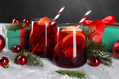 Delicious Sangria drink in glasses and Christmas decorations on grey textured table, closeup