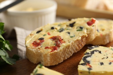 Photo of Tasty butter with olives, chili pepper, parsley and bread on table, closeup