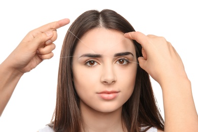 Young woman having eyebrow correction procedure on white background