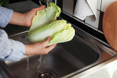 Photo of Woman washing fresh Chinese cabbage in sink, closeup