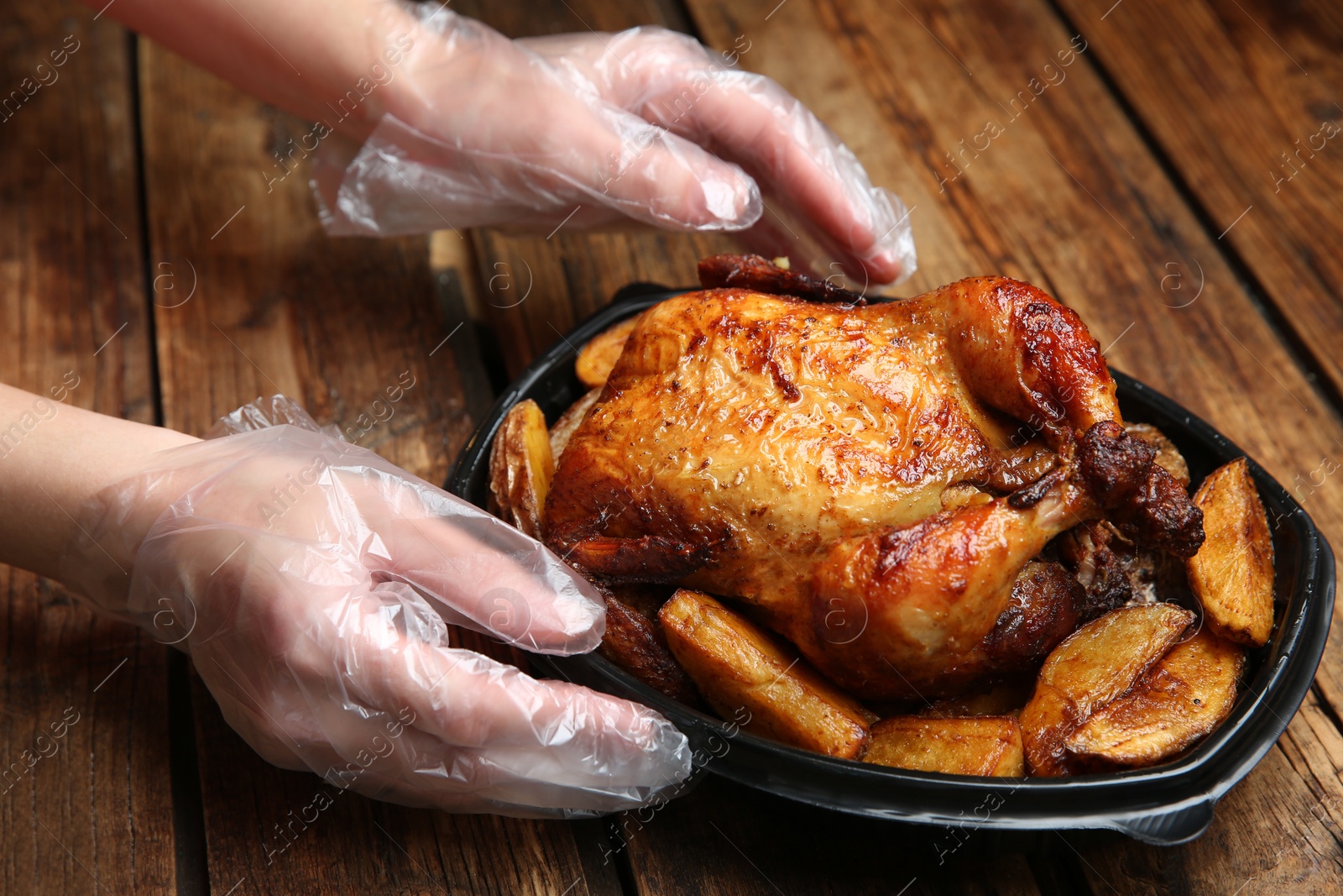 Photo of Waiter with container of fresh prepared meal at wooden table, closeup. Food delivery service