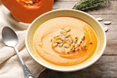 Photo of Bowl with tasty pumpkin soup served on wooden table