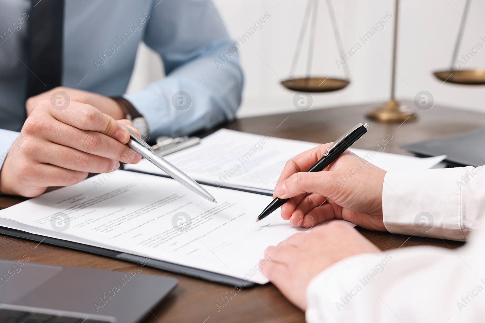 Photo of Lawyers working with documents at wooden table indoors, closeup