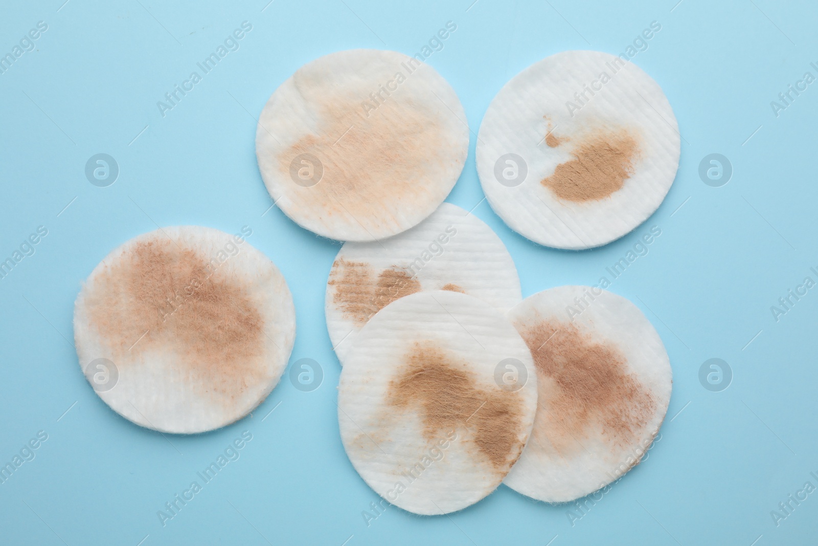 Photo of Dirty cotton pads after removing makeup on light blue background, flat lay