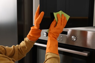 Photo of Woman with microfiber cloth cleaning microwave in kitchen, closeup