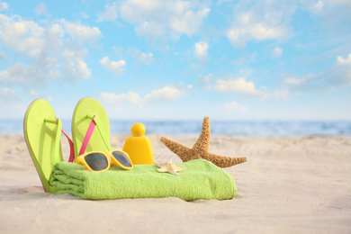 Different stylish beach objects and starfish on sand near sea