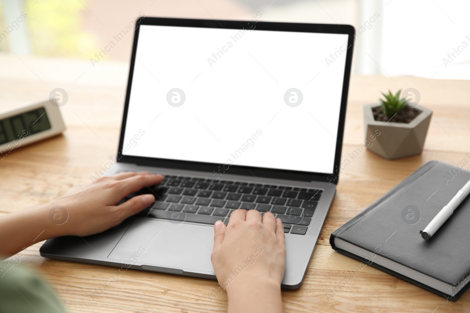 Photo of Woman working with modern laptop at wooden table, closeup. Space for design