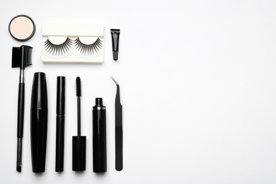 Photo of Composition with false eyelashes and other makeup products on white background, top view