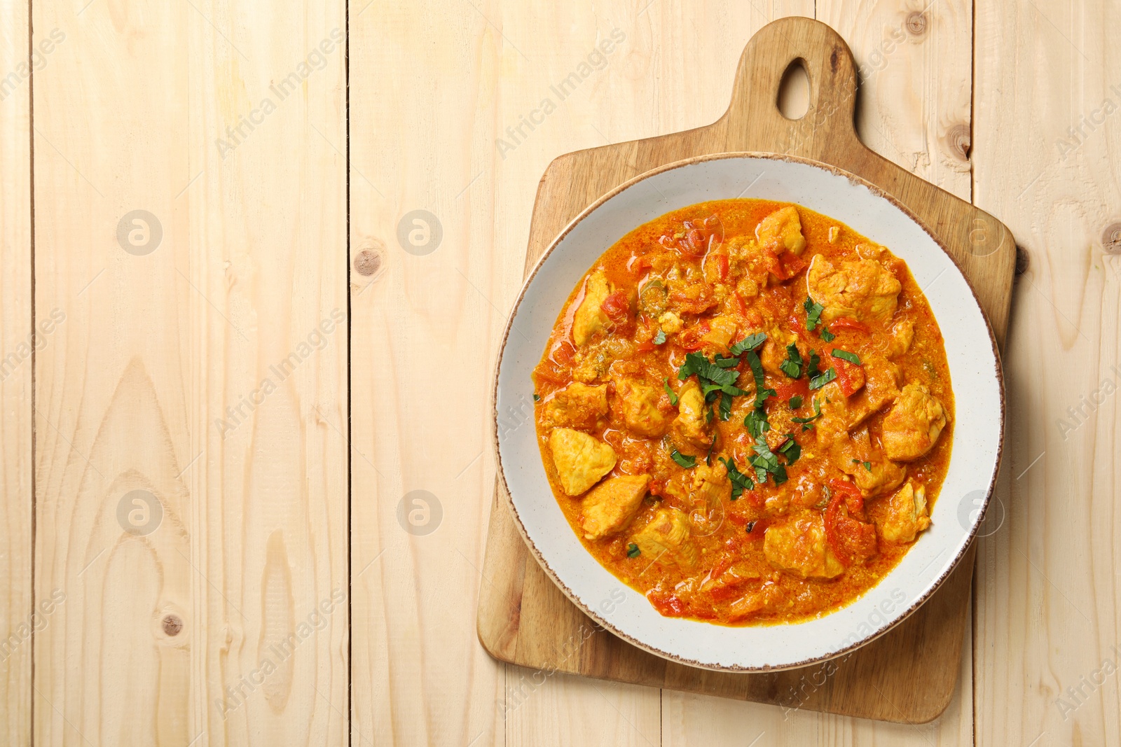 Photo of Delicious chicken curry on wooden table, top view. Space for text