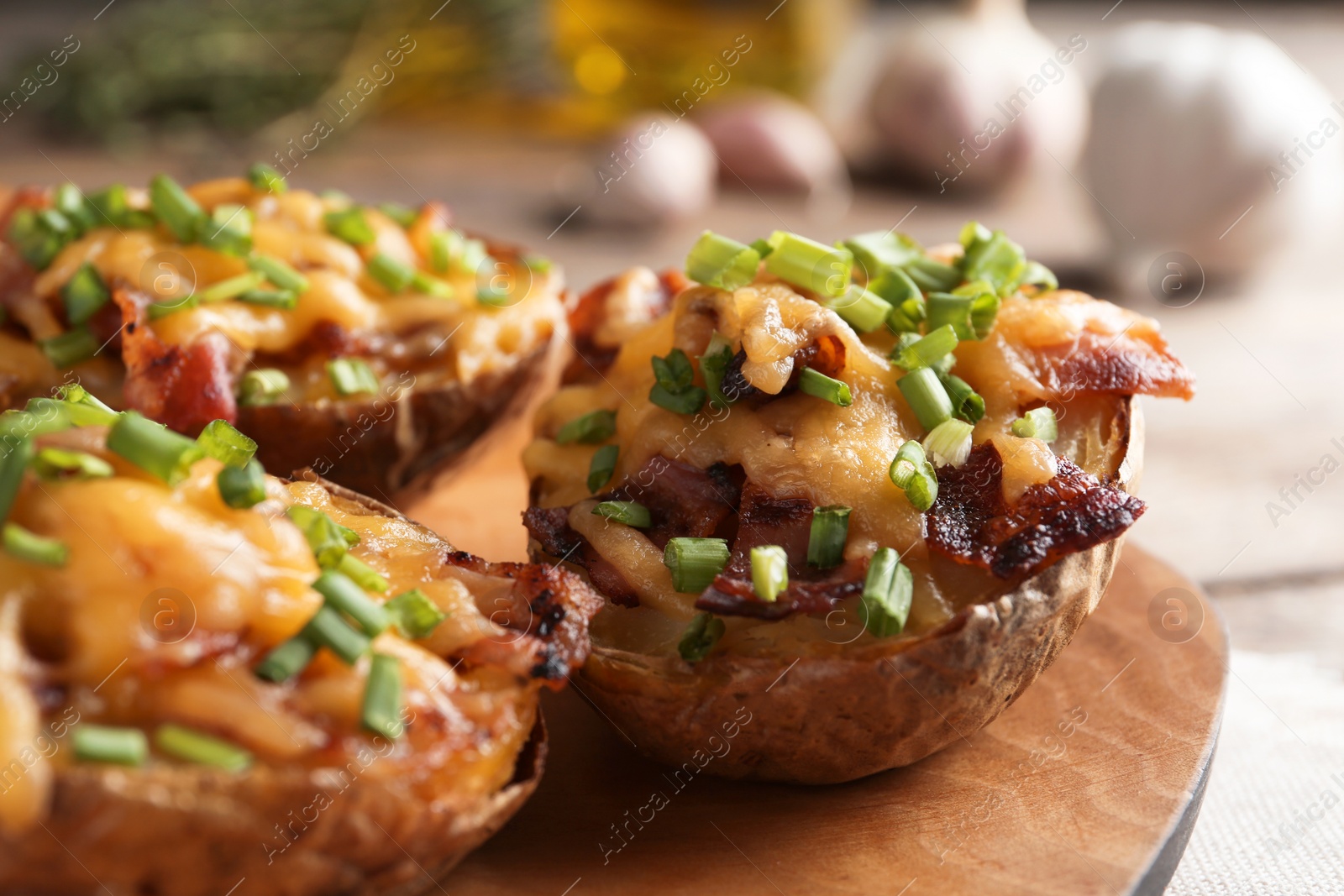 Photo of Board of baked potatoes with cheese and bacon on table, closeup