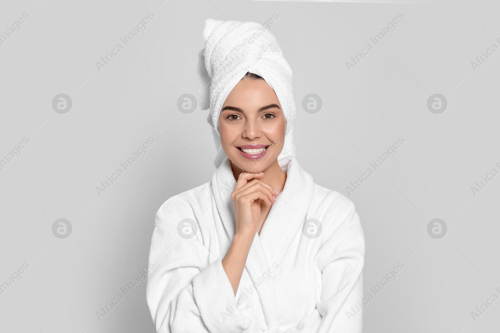 Photo of Young woman in bathrobe with towel on light grey background. Spa treatment