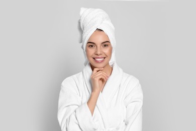 Young woman in bathrobe with towel on light grey background. Spa treatment