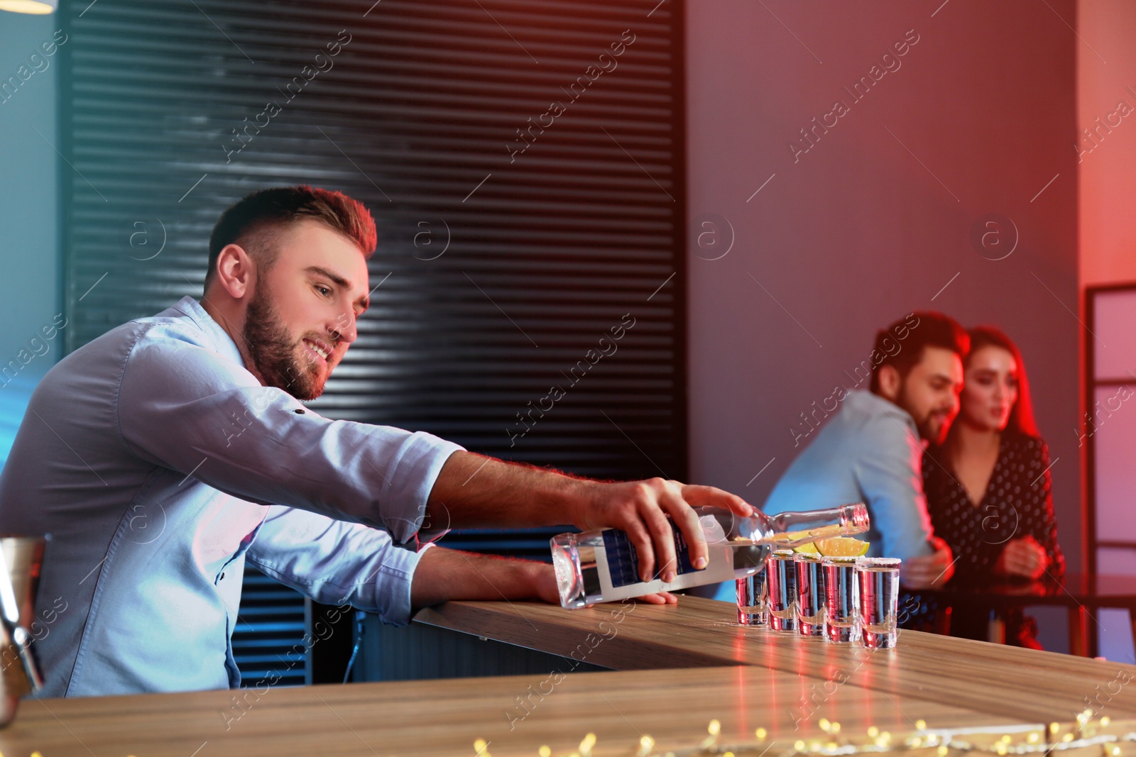 Photo of Bartender pouring Mexican Tequila into shot glasses at bar counter