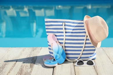 Beach accessories on wooden deck near outdoor swimming pool, space for text