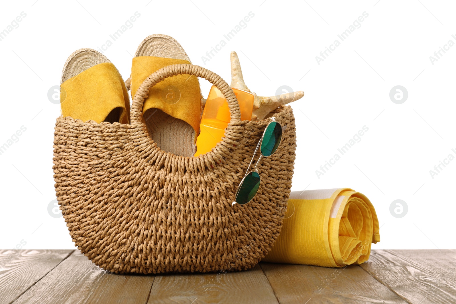 Photo of Stylish bag with beach accessories on wooden table against white background