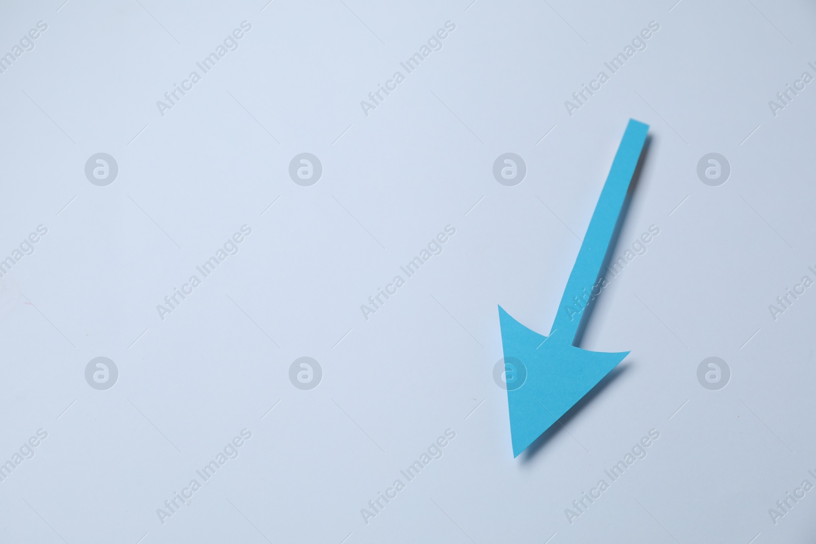 Photo of Light blue paper arrow on white background, top view. Space for text