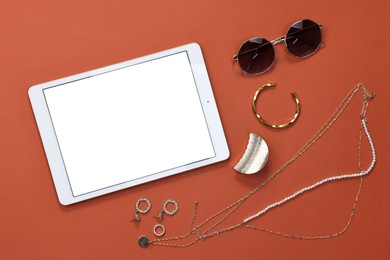 Photo of Modern tablet, sunglasses and bijouterie on color background, flat lay. Space for text