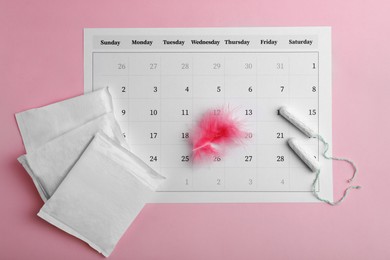 Photo of Menstrual pads, tampons, feather and calendar on pink background, flat lay