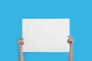 Woman holding blank poster on blue background, closeup