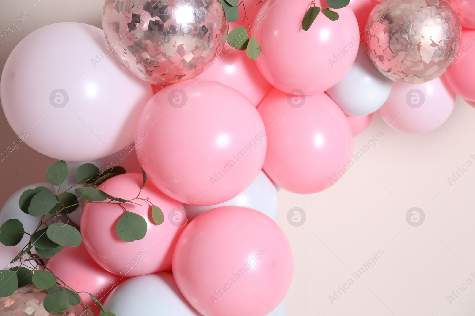 Photo of Beautiful composition with balloons and green leaves on beige background, closeup