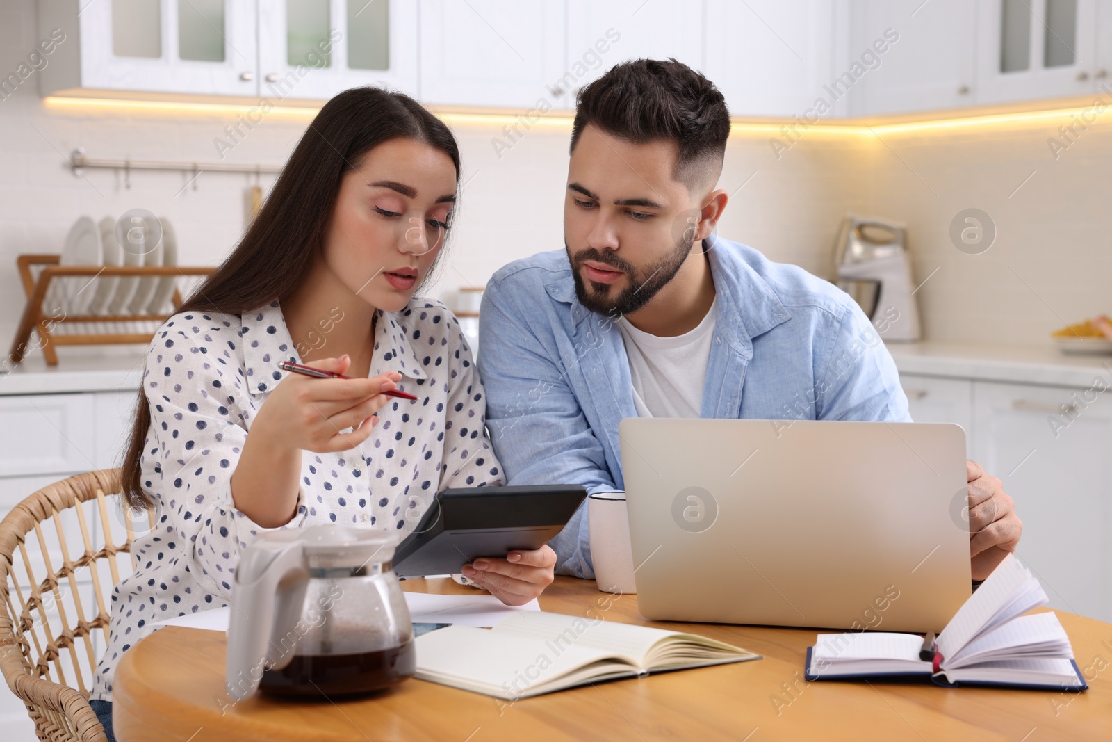 Photo of Young couple discussing family budget in kitchen