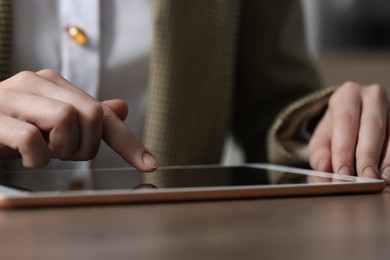 Photo of Closeup view of woman using modern tablet at table on blurred background